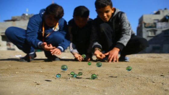 Palestinian children play marbles in a street in Gaza City on January 11, 2017. / AFP / MOHAMMED ABED
